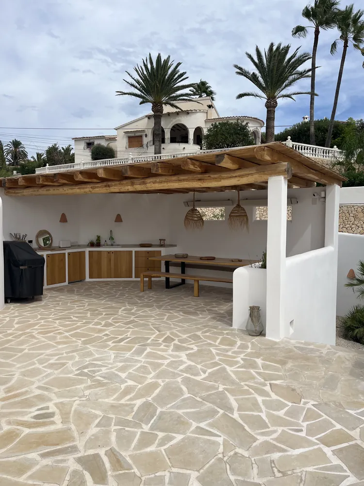 Cocina exterior de obra cubierta por una estructura de madera